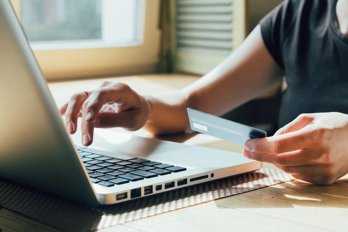 Persona pagando en línea con tarjeta de crédito y su laptop